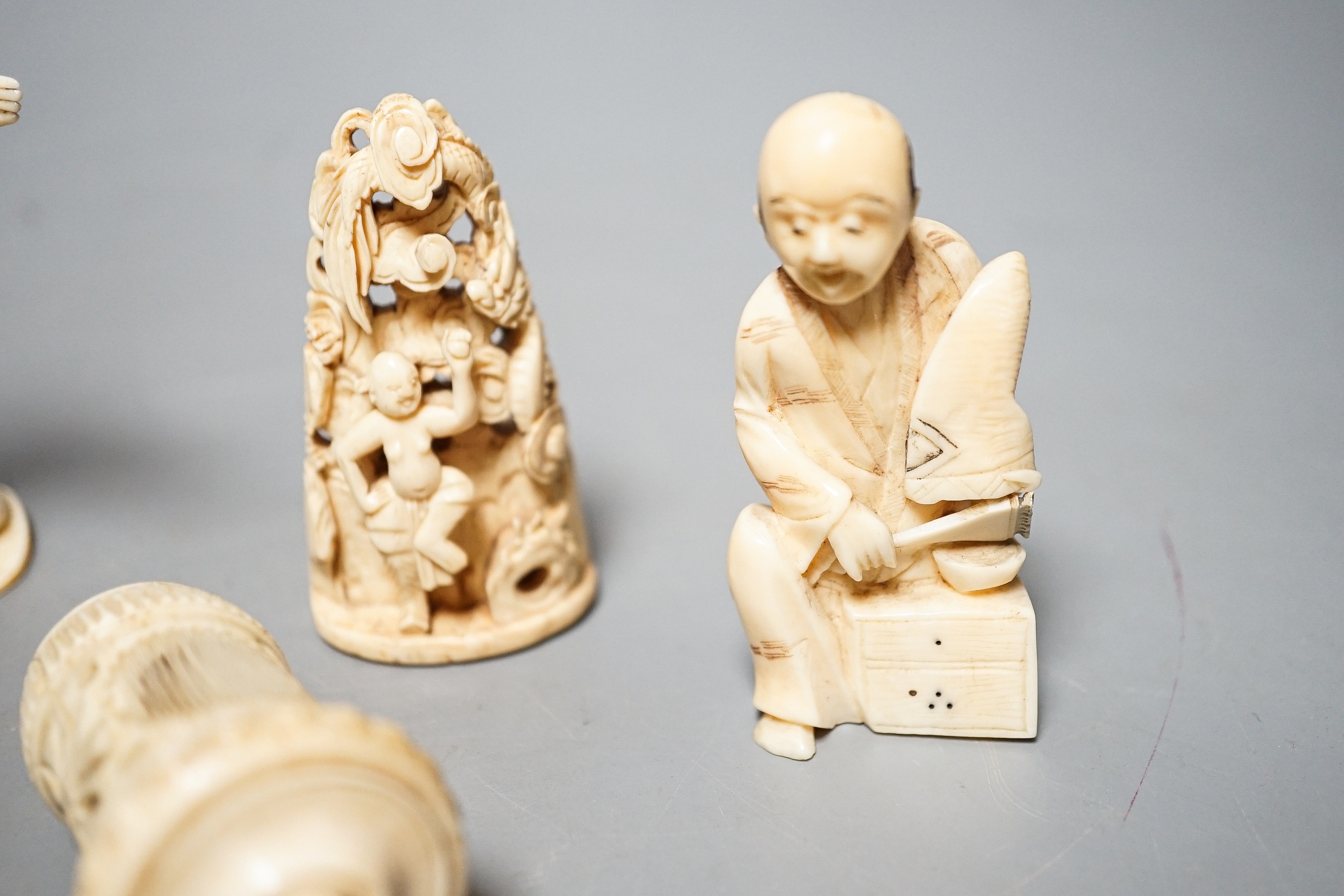 Three Japanese Ivory figures of men, a similar bezique marker, a Japanese staghorn single section inro with ivory manju, a Chinese ivory carving and a bone needlework container